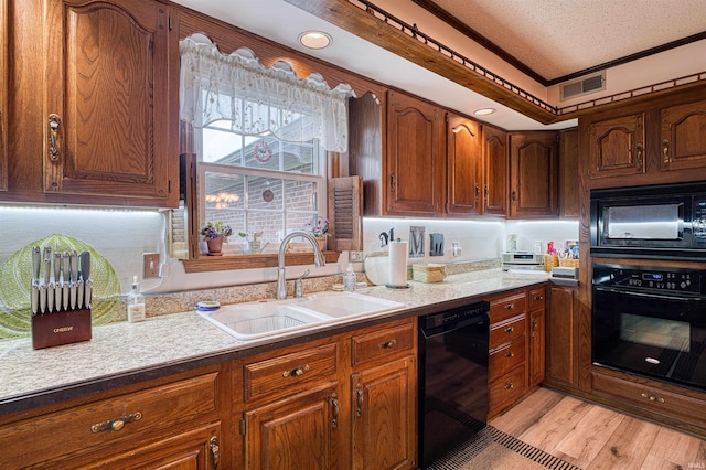 kitchen with black appliances, a sink, ornamental molding, light wood-style floors, and brown cabinetry