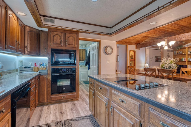 kitchen with black appliances, a textured ceiling, dark countertops, pendant lighting, and light wood finished floors