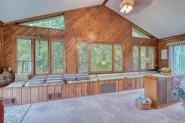 kitchen featuring vaulted ceiling, wood walls, carpet, and a ceiling fan