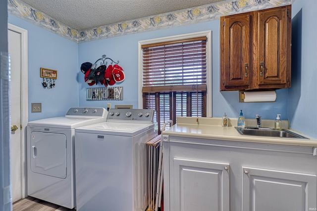 washroom featuring washing machine and dryer, a textured ceiling, and cabinet space