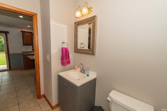 bathroom featuring toilet, vanity, baseboards, and tile patterned floors