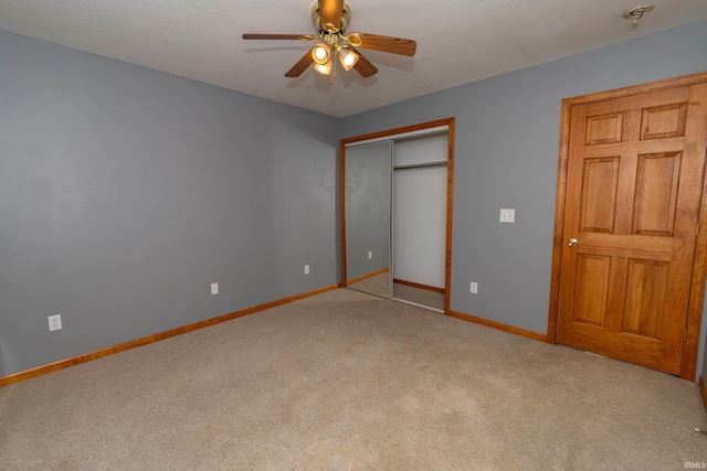 unfurnished bedroom featuring carpet, baseboards, a closet, and ceiling fan