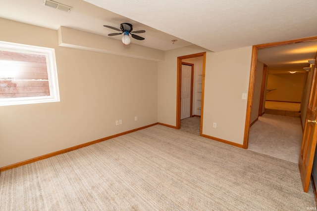 unfurnished room with a ceiling fan, light carpet, and baseboards