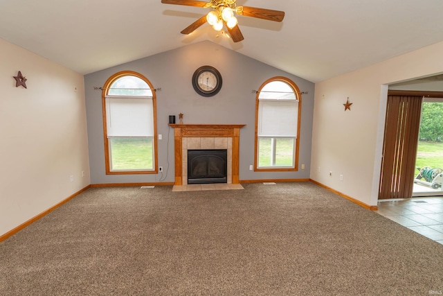unfurnished living room with lofted ceiling, carpet floors, baseboards, a tile fireplace, and a ceiling fan