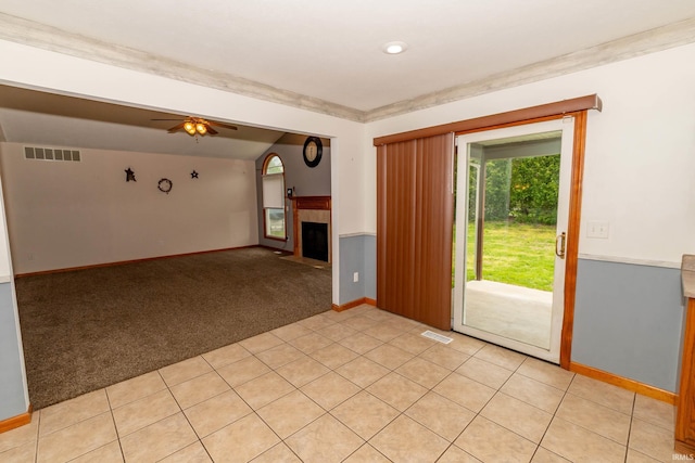 empty room with light carpet, baseboards, a fireplace with flush hearth, and ceiling fan