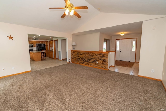 unfurnished living room with lofted ceiling, light tile patterned flooring, light carpet, baseboards, and a ceiling fan