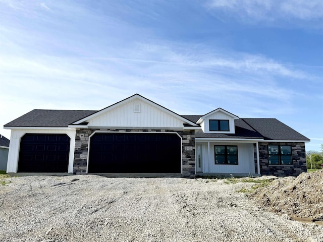 view of front of property featuring an attached garage, stone siding, and driveway