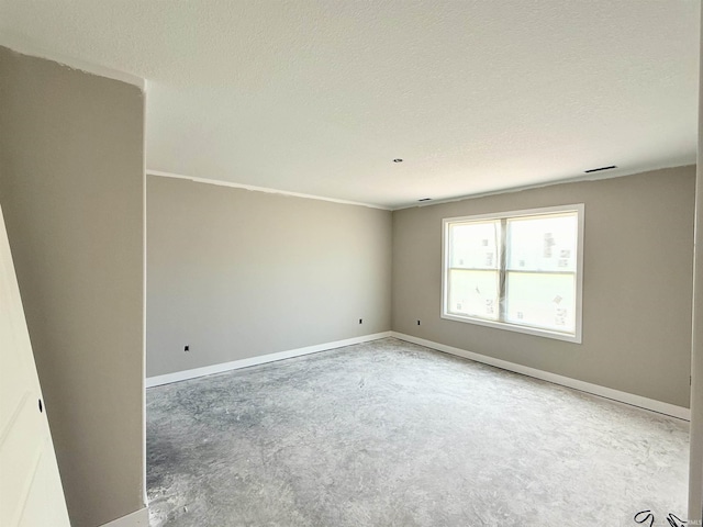 unfurnished room with unfinished concrete floors, a textured ceiling, baseboards, and ornamental molding