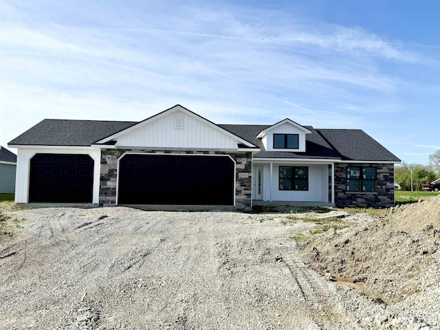 modern farmhouse style home with a garage, stone siding, and driveway
