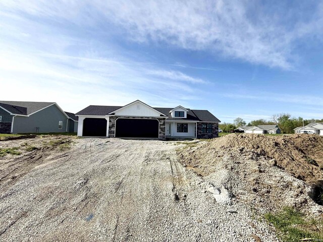 view of front of home with a garage, dirt driveway, and stone siding