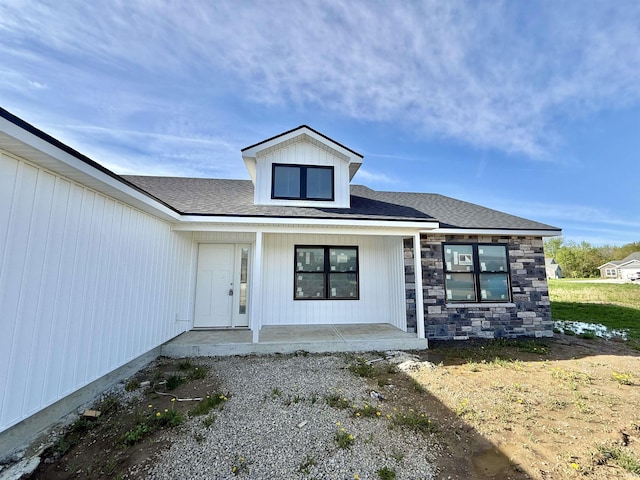 doorway to property featuring a porch and stone siding
