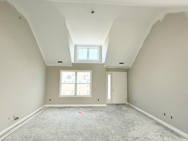unfurnished living room with lofted ceiling and baseboards