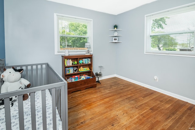 4070 W 3rd St, Bloomington, IN 47404 - bedroom with hardwood / wood-style flooring, multiple windows, baseboards, and a nursery area