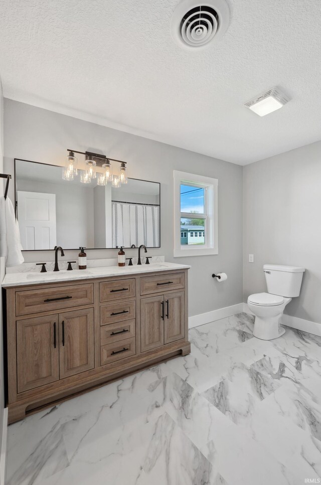 5363 W Warren Ave, Silver Lake, IN 46982 - full bathroom with baseboards, toilet, a textured ceiling, double vanity, and marble finish floors