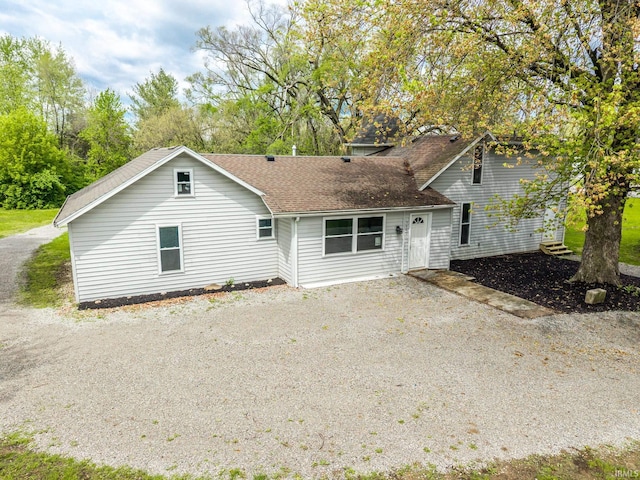 back of house featuring driveway and a shingled roof