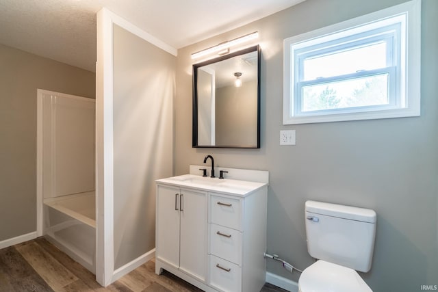 bathroom featuring wood finished floors, toilet, vanity, and baseboards