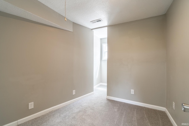 unfurnished room with carpet, baseboards, and a textured ceiling