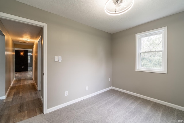 unfurnished room with baseboards, a textured ceiling, and wood finished floors