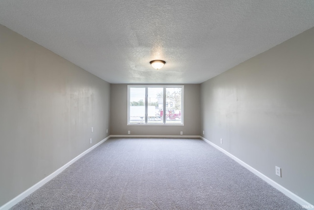 carpeted empty room featuring a textured ceiling and baseboards