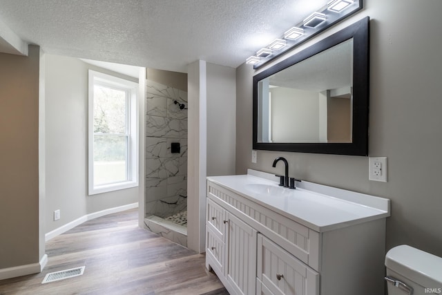 full bath with a textured ceiling, a shower stall, wood finished floors, vanity, and toilet