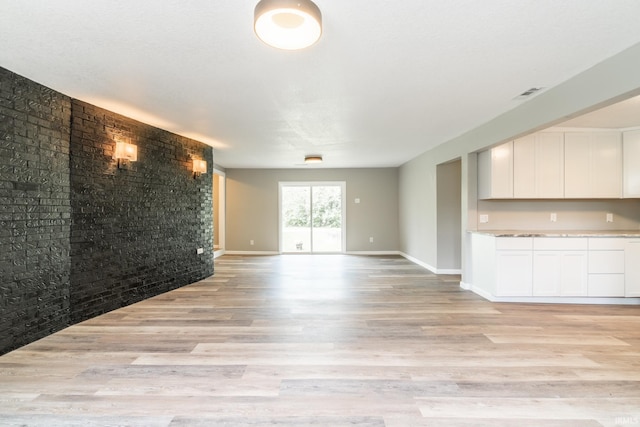 unfurnished living room with light wood-type flooring and baseboards
