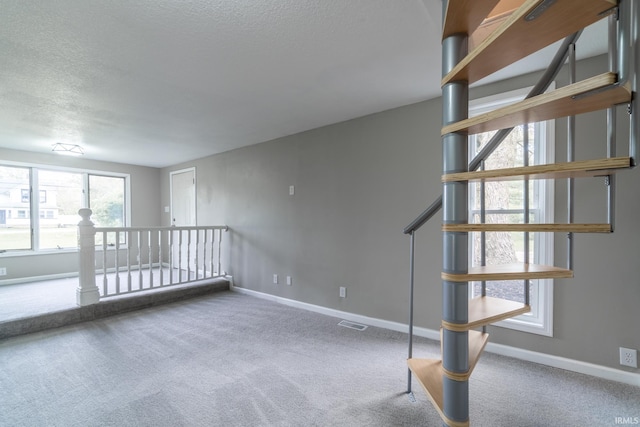 carpeted empty room with a textured ceiling and baseboards