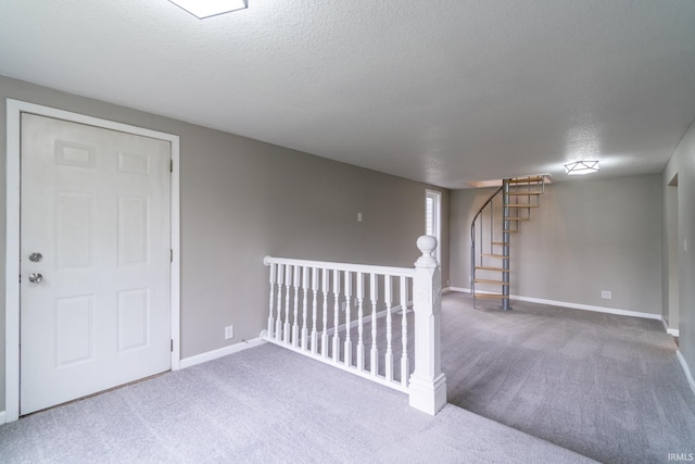 finished below grade area featuring carpet floors, a textured ceiling, and baseboards