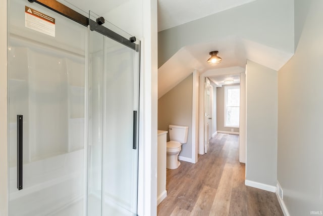 full bath with toilet, a shower stall, wood finished floors, baseboards, and lofted ceiling