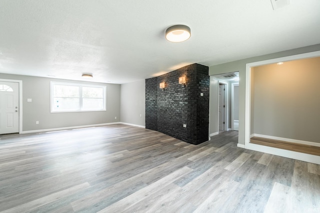 unfurnished living room featuring wood finished floors and baseboards