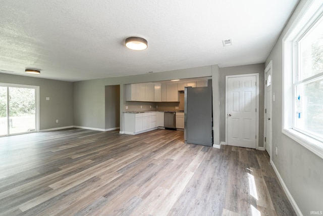 unfurnished living room with wood finished floors, baseboards, and a textured ceiling