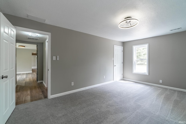 spare room featuring carpet flooring, a textured ceiling, and baseboards