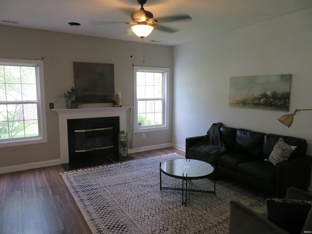 living area featuring healthy amount of natural light, wood finished floors, baseboards, and a ceiling fan