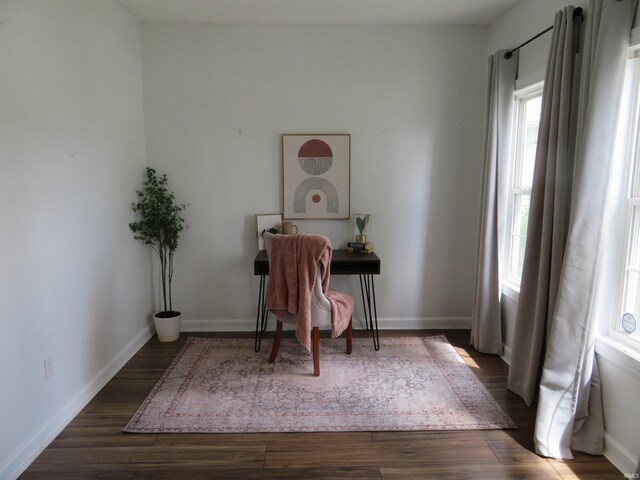 living area featuring healthy amount of natural light, dark wood-style flooring, and baseboards