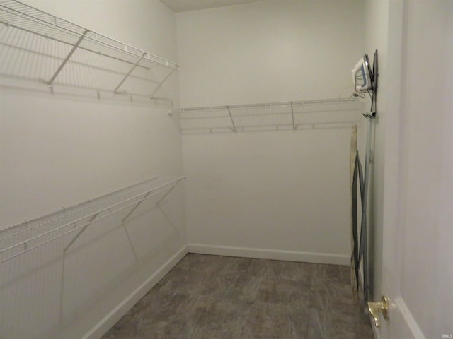 walk in closet with dark wood-style floors