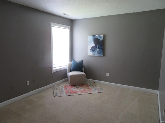 living area featuring carpet flooring, baseboards, and a textured ceiling