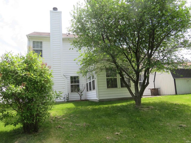 back of property featuring a chimney and a yard