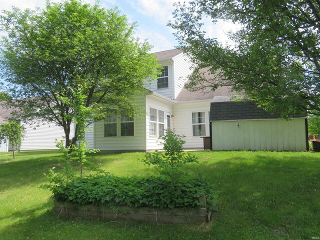 back of property featuring a yard and a shingled roof