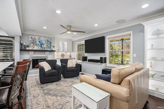 living area featuring crown molding, ceiling fan, a fireplace, recessed lighting, and wood finished floors