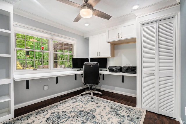 office space featuring built in study area, crown molding, a ceiling fan, dark wood-type flooring, and baseboards