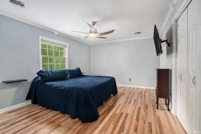 bedroom with crown molding, light wood finished floors, baseboards, a ceiling fan, and a closet