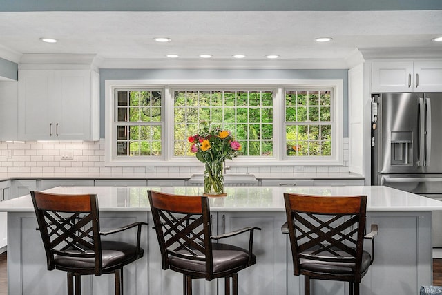 kitchen featuring crown molding, light countertops, white cabinets, backsplash, and a kitchen island