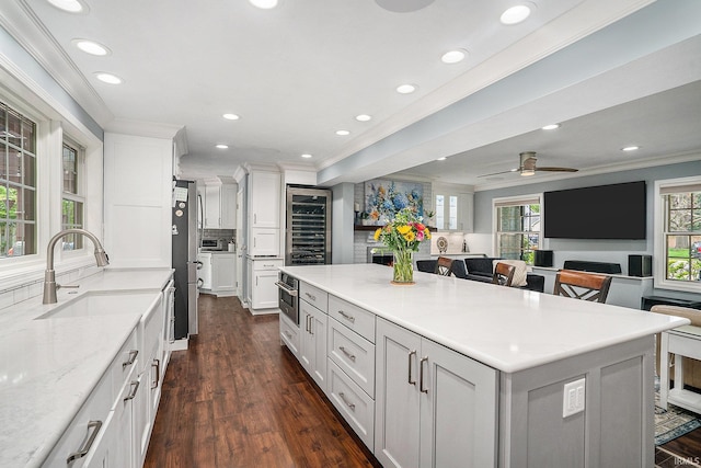 kitchen featuring wine cooler, a sink, ornamental molding, open floor plan, and recessed lighting