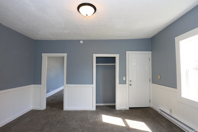 455 E Barner St, Frankfort, IN 46041 - unfurnished bedroom with a baseboard heating unit, a wainscoted wall, carpet, a closet, and a textured ceiling