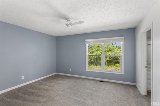 unfurnished room with carpet floors, ceiling fan, baseboards, and a textured ceiling
