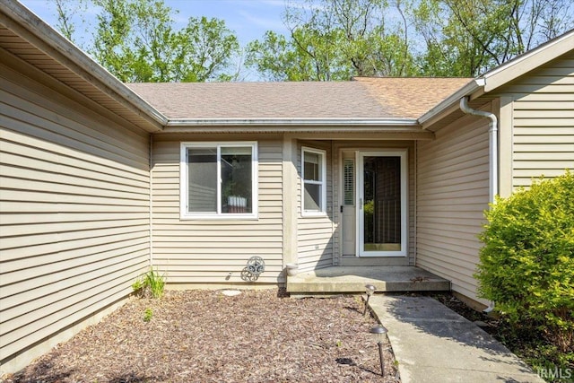 view of exterior entry with a shingled roof
