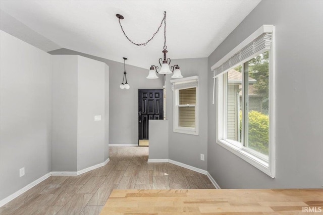 unfurnished dining area featuring a chandelier and baseboards