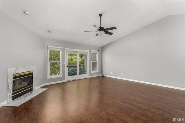 unfurnished living room featuring ceiling fan, lofted ceiling, baseboards, and a high end fireplace