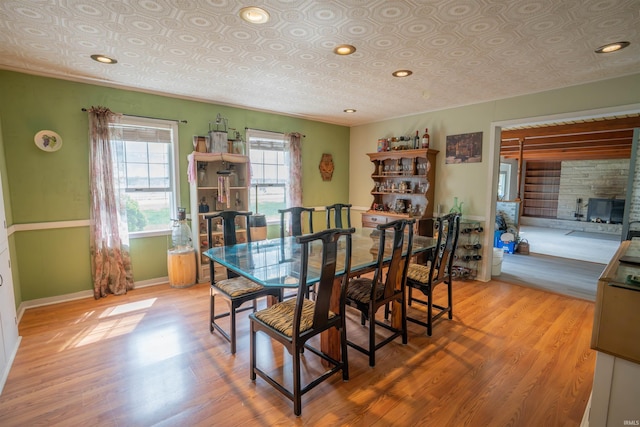 dining room featuring light wood-type flooring, baseboards, an ornate ceiling, and crown molding