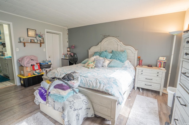 bedroom with ornamental molding, light wood-style floors, and a closet