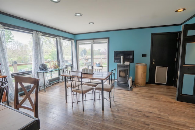 dining area featuring ornamental molding, wood finished floors, recessed lighting, and a wood stove
